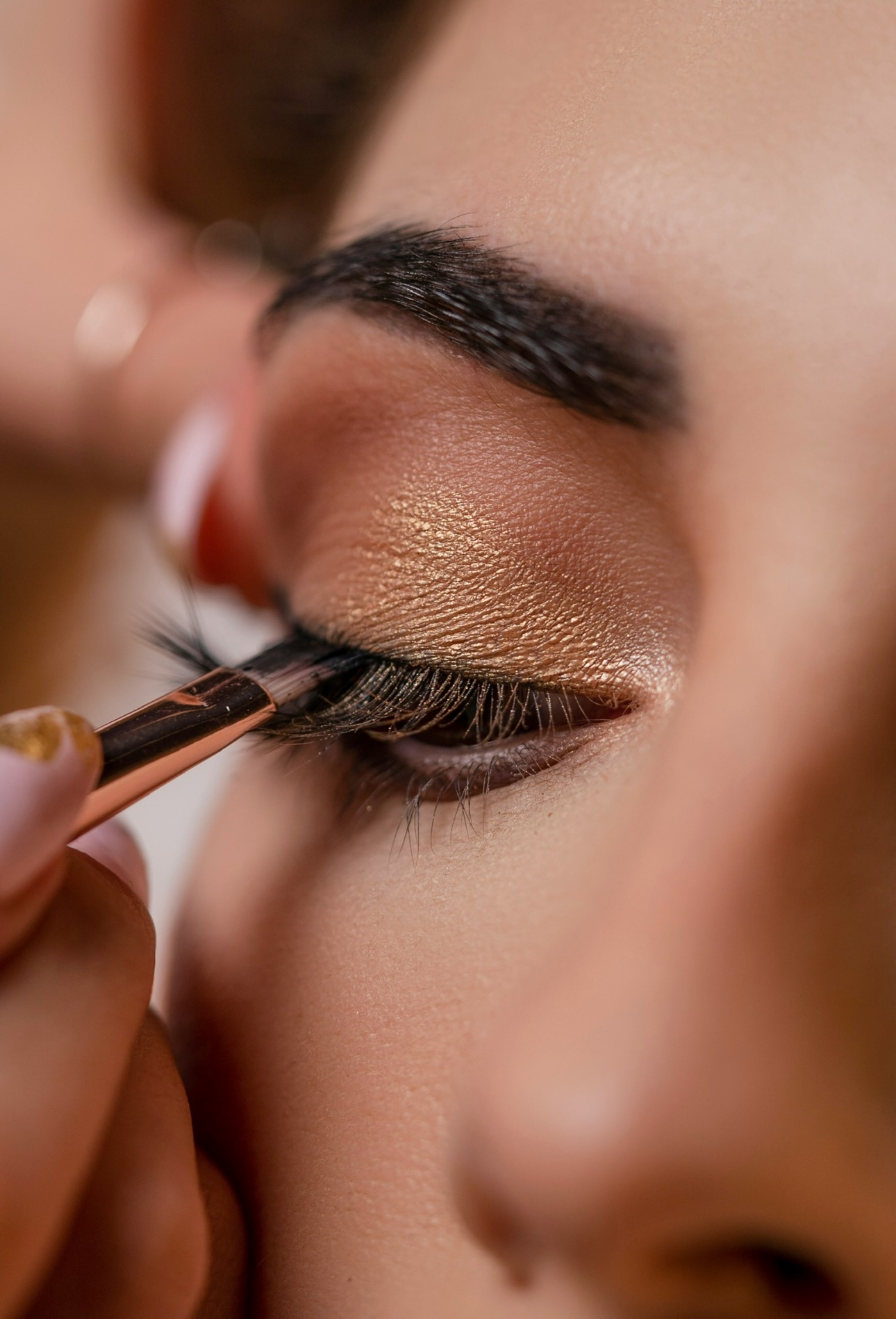 Makeup artist applying false lashes and gold eyeshadow